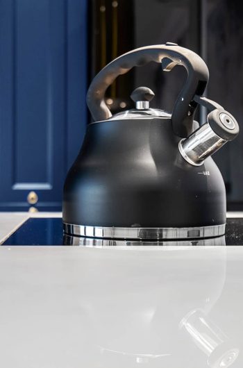 Blat w kuchni wykonany ze spieku kwarcowego Marazzi ''Statuario'' lux. Na blacie płyta indukcyjna i czajnik.