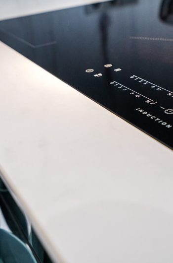 Czarna płyta indukcyjna na blacie wykonanym ze spieku kwarcowego Marazzi ''Statuario'' lux.