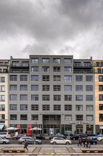Na zdjęciu widzimy nowoczesny, wielokondygnacyjny budynek mieszkalno-użytkowy zlokalizowany przy Markgrafenstr. 35, w Berlinie. Architektura budynku jest zróżnicowana – składa się z trzech głównych części, które różnią się kolorem.