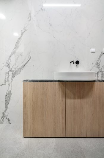 Na zdjęciu przedstawione szafki w łazience, blat wykonany z granitu jurassic grey, a na nim biała umywalka.