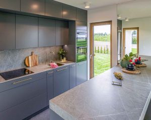 Zdjęcie przedstawia nowoczesną kuchnię z szarymi szafkami i blatem wykonanym ze spieku kwarcowego Neolith. 