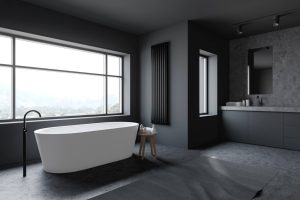 Na zdjęciu widoczna jest nowoczesna, minimalistyczna łazienka utrzymana w ciemnej kolorystyce. Dominują odcienie grafitu, czerni i szarości, co nadaje wnętrzu elegancki, luksusowy i nieco surowy charakter.